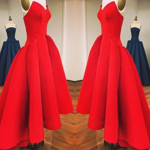 Detail of red sweetheart neckline evening dress with high-low hem and pleated satin fabric