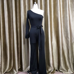 Detail of black one-shoulder jumpsuit with long sleeve and waist tie on a dress form