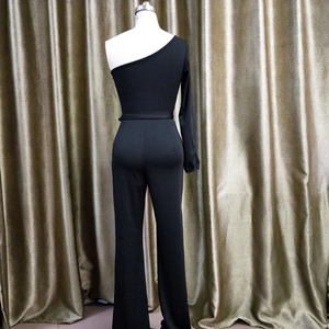 Detail of black one-shoulder long sleeve jumpsuit featuring slim fit waist and wide leg cut