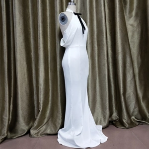 Detail of white evening gown featuring halter neck and black bow tie decoration