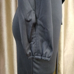 Detail of elastic ruffled cuffs on a black asymmetric jumpsuit with smooth fabric texture