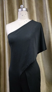 Detail of elegant black one-shoulder jumpsuit with draped sleeve on a mannequin