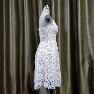 Détails de broderie en dentelle florale blanche sur une robe de cocktail sans manches