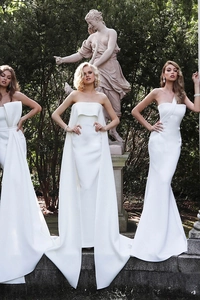 Detailed view of three elegant white satin evening dresses in a classical garden setting