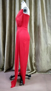 Detail of red one-shoulder jumpsuit featuring elegant side drape and pleated waist design