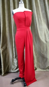Detail of red strapless jumpsuit featuring elegant waistline and dramatic draped fringe panel