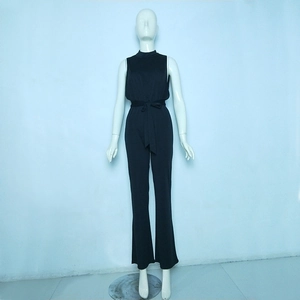 Detail of black sleeveless jumpsuit showing high neck and waist tie with flared legs