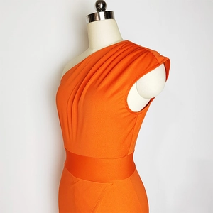 Detailed close-up of bright orange one-shoulder dress with elegant shoulder pleats