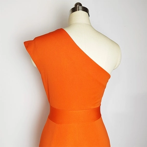 Detail of vibrant orange one-shoulder dress showing waist cinch and premium woven fabric