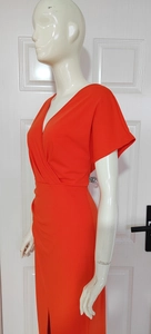 Close-up of a bright orange V-neck wrap dress with side slit and high waist