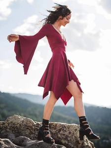 Detail of burgundy V-neck dress with dramatic ruffle sleeves and asymmetric hemline