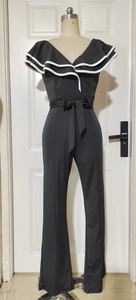 Detail of black jumpsuit with white-trimmed ruffles and matching waist tie belt