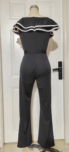 Detail of elegant black jumpsuit with white contrast ruffles and hidden back zipper