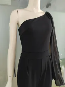 Détail d'une combinaison noire à une épaule avec manche cape et taille plissée élégante