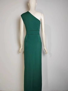 Back view of a green one-shoulder evening gown with waist seam detail on a white mannequin