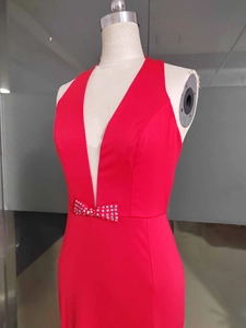 Dettaglio dell'abito da sera rosso con scollo a V, inserto in rete e fiocco con strass lucidi