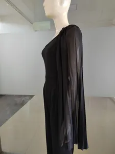 Détail d'une combinaison noire à une épaule avec manche cape en mousseline et taille ajustée