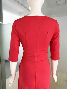 Détail de robe rouge ajustée montrant la fermeture éclair invisible et les plis à la taille