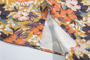 Detail of the side slit and floral print on a yellow Hawaiian beach vacation shirt