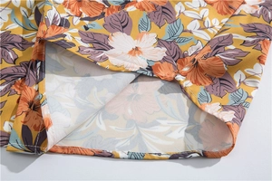 Detailed close-up of the hem stitching and tropical floral print on a yellow summer shirt