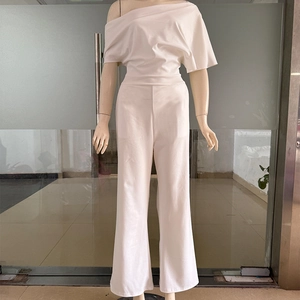 Detail of white one-shoulder jumpsuit featuring elegant waist pleats and wide-leg design