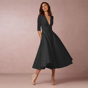 Détail d'une robe noire élégante à col en V profond, manches mi-longues et jupe évasée