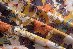 Detail of Hawaiian floral fabric showing mustard yellow base and tropical flower patterns