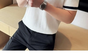 Detail of white knit polo shirt featuring herringbone texture and black striped cuffs