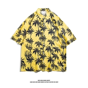 Detail of yellow short-sleeved Hawaiian shirt with black palm tree patterns and white buttons