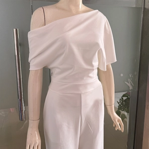 Detail of white one-shoulder jumpsuit featuring elegant pleats and a fitted waistline