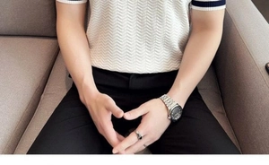 Detailed view of white knit polo shirt featuring navy blue striped cuffs and wave pattern