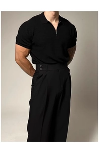 Detail of men's black knit polo shirt with zipper collar and double-button pleated trousers