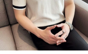 Detail of white knit polo shirt featuring wave texture and black striped cuffs