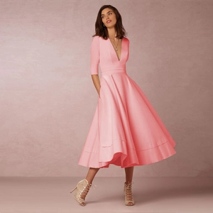 Détail d'une élégante robe midi rose à col en V, manches mi-longues et jupe évasée