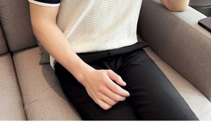 Close-up of white ripple-textured knit polo shirt and black slim-fit trousers on model