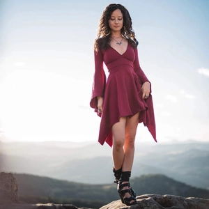 Elegant burgundy deep V-neck dress with ruffle sleeves and asymmetrical hem in outdoor setting