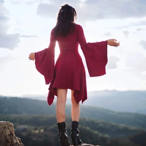 Deep red bodycon dress with oversized bell sleeves and asymmetrical hem on a mountain peak