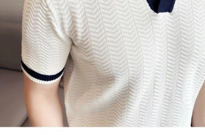 Close-up of white knitted polo shirt fabric with vertical herringbone texture and navy ribbing