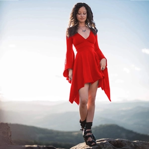 Red deep V-neck dress with flare sleeves and asymmetrical hem on a scenic mountain view