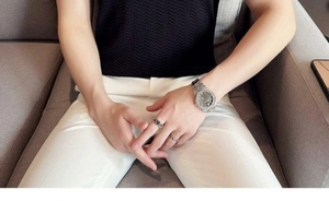 Detail shot of men's black knit polo shirt texture with white pants and classic silver watch