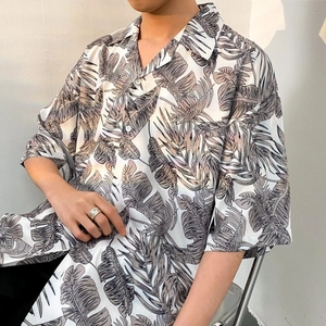 Detailed view of the tropical leaf print and clean Cuban collar on a white summer shirt