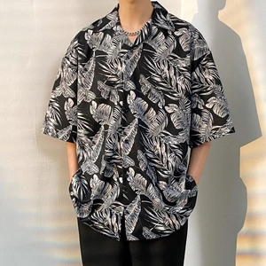 Detail of oversized black short sleeve shirt featuring white tropical leaf pattern print