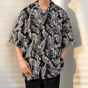 Detail view of tropical leaf print on black oversized short-sleeved Hawaiian shirt for men