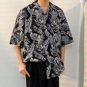 Detail of tropical palm leaf pattern on a draped black oversized Hawaiian shirt for men