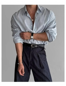 Dettaglio di camicia a righe azzurre in cotone lino con pantaloni a vita alta con pieghe
