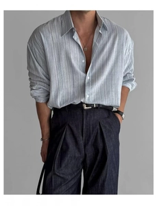 Dettaglio camicia da lavoro a righe azzurre con pantaloni in denim a pieghe e cintura