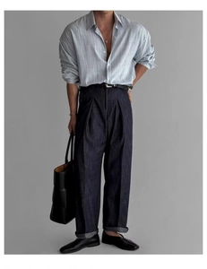Dettaglio di camicia da lavoro a righe azzurre con jeans a gamba larga blu scuro e borsa
