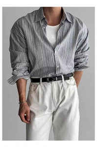 Dettaglio di camicia a righe vintage abbinata a gilet bianco e pantaloni in cotone e lino