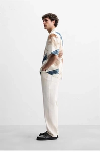 Male model side view in abstract oil painting print shirt and beige loose trousers