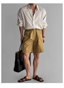 Dettaglio camicia a righe da uomo in lino con pantaloncini giallo senape e borsa intrecciata